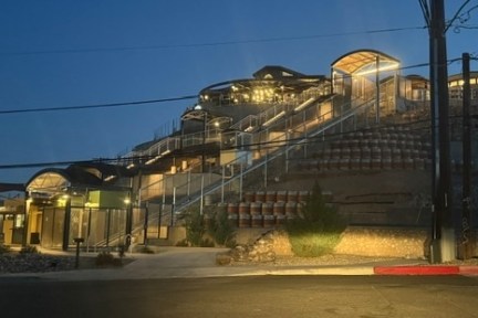 Illuminated hillside building with multiple levels and pathways at night.