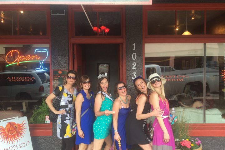 Six women posing happily outside a wine tasting room.