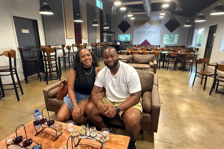 A couple sitting on a couch in a winery tasting room with empty chairs.