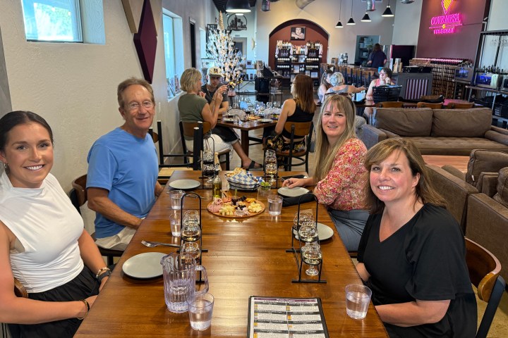 Four people seated at a table in a cozy restaurant, smiling at the camera.