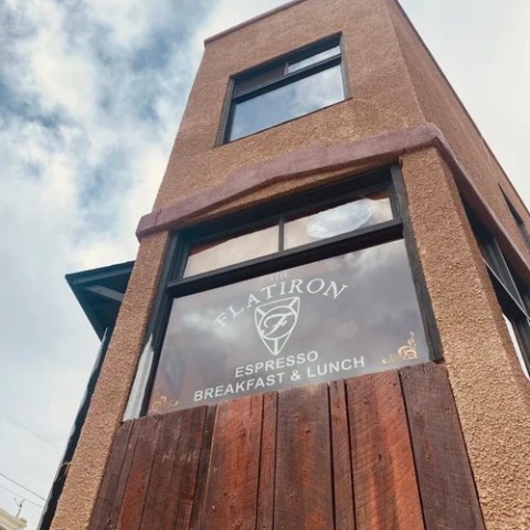 Tall building with a sign for espresso, breakfast, and lunch under a partly cloudy sky.