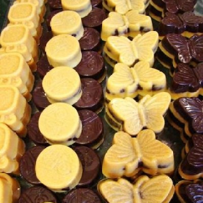 Assorted chocolates in various shapes, including circles and butterflies, arranged in rows.