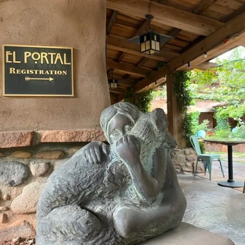 Bronze sculpture of a child hugging a wolf near El Portal Registration sign.