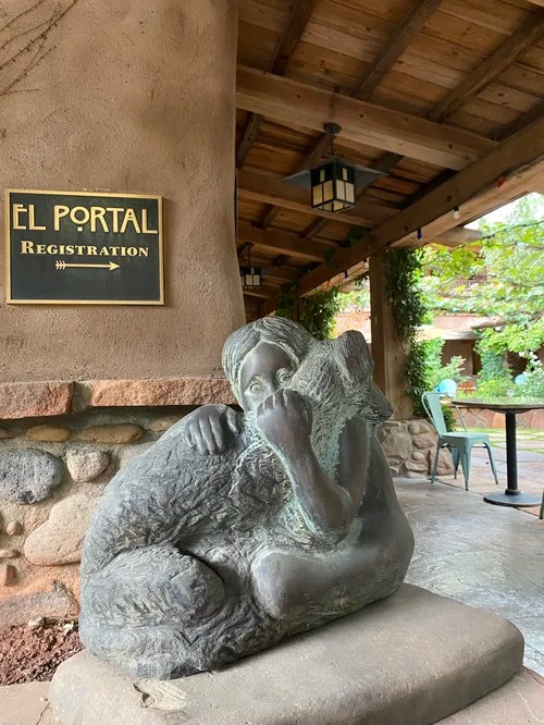 Bronze sculpture of a child hugging a wolf near El Portal Registration sign.