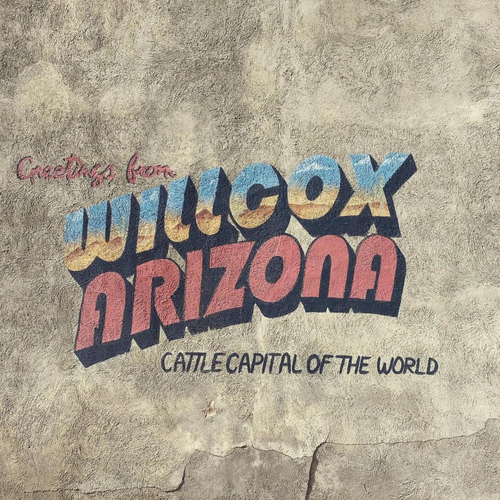 Retro mural reads 'Greetings from Willcox, Arizona: Cattle Capital of the World' on a textured wall.