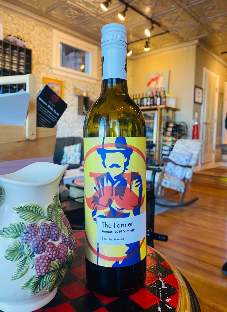 Wine bottle labeled 'The Farmer' on a table next to a ceramic pitcher, in a cozy room.